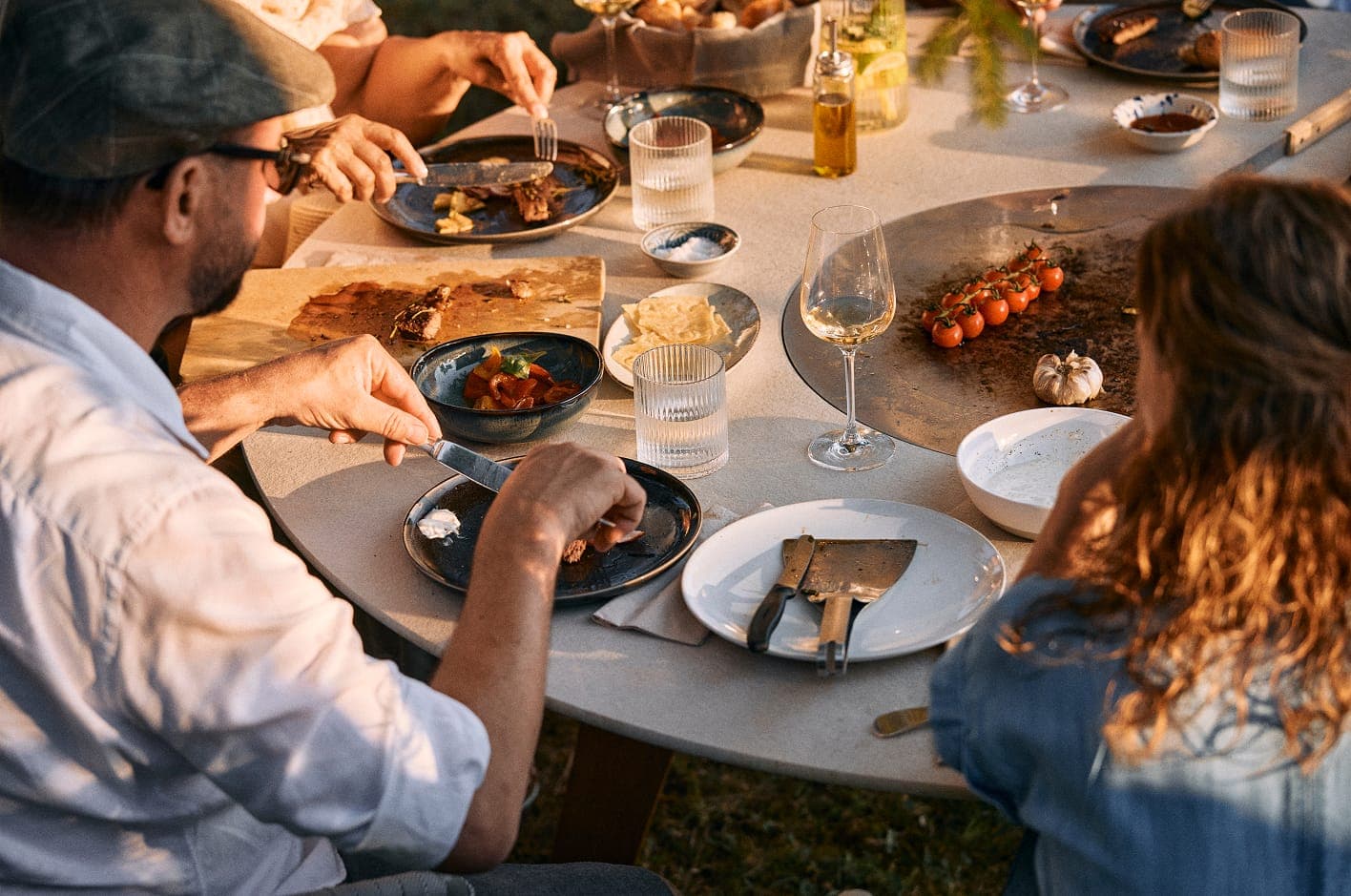 Freunde essen gemeinsam am gedeckten Q-Olento